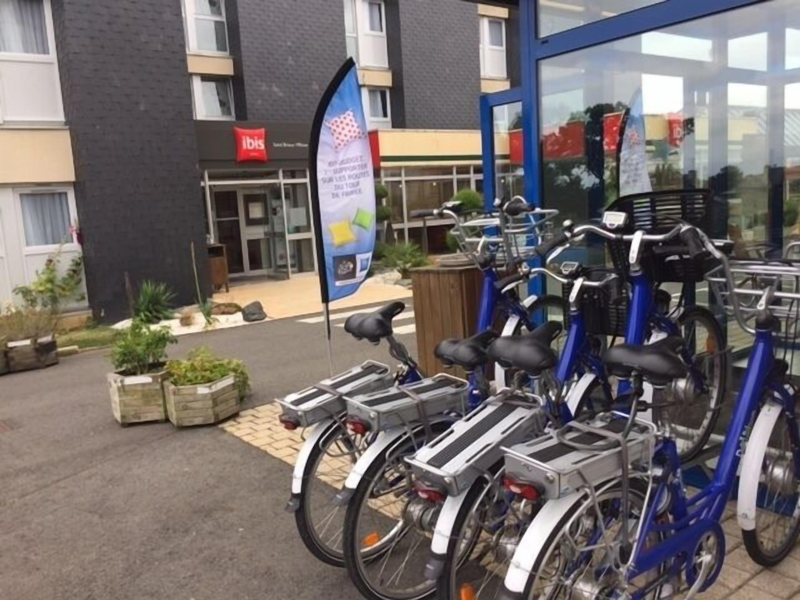 A row of bicycles parked outside a building with a sign that reads "ibis".