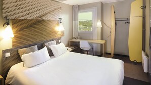 Una camera d'albergo con un letto, una scrivania, una sedia e vista sull'esterno.