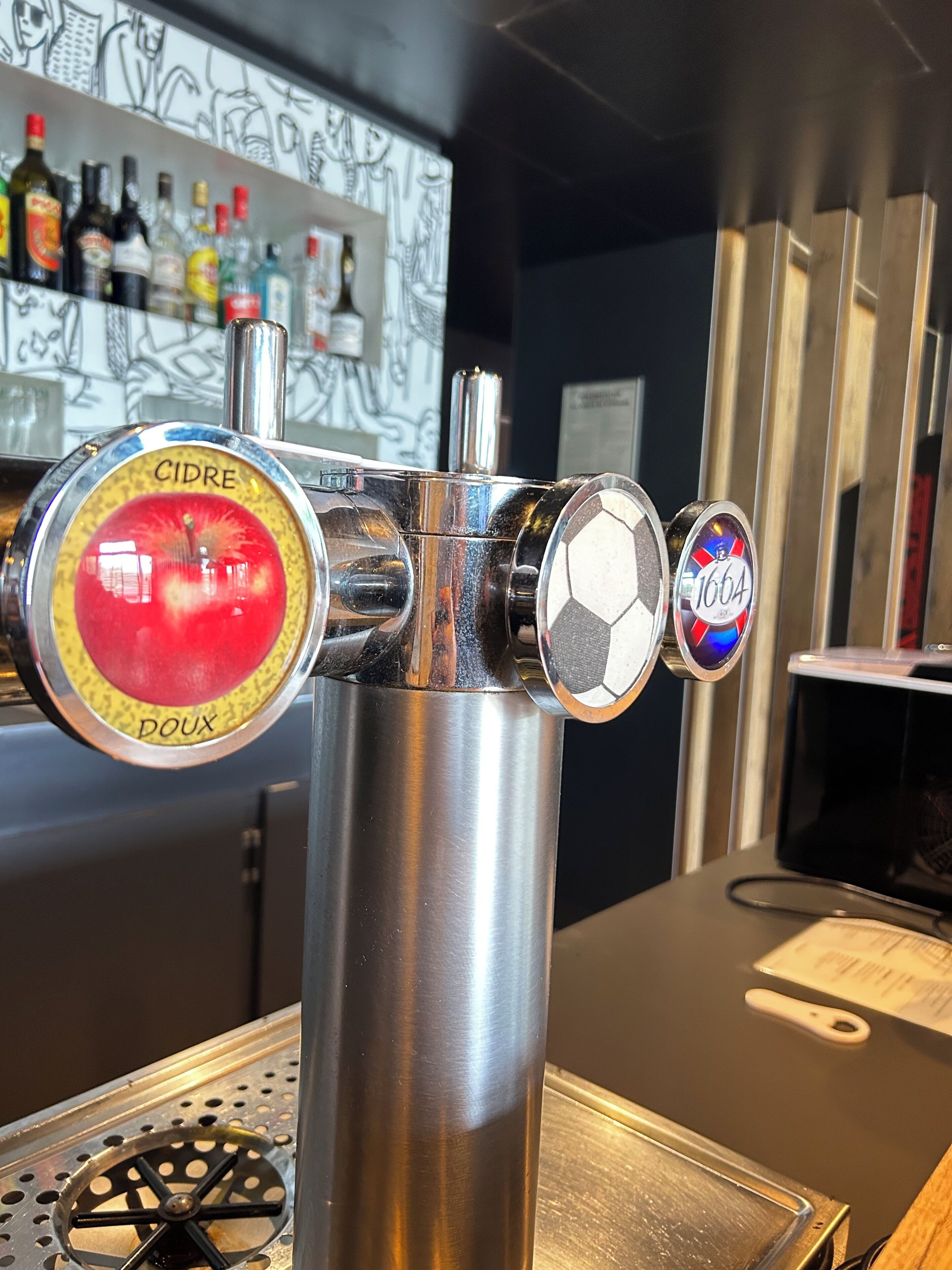 A tap with labels 'CIDER' and 'DOUX' and a beer tap labeled '1664'.