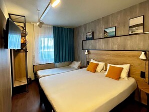 Habitación de hotel con dos camas, televisión, ventilador de techo y obras de arte en la pared.