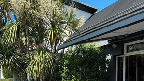 An outdoor seating area with a grey sofa and yellow chairs, surrounded by lush greenery and a modern building. - ibis Saint Malo La Madeleine (Saint-Malo)