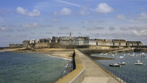 A coastal cityscape with a prominent castle, a promenade, and a marina with boats. - ibis Saint Malo La Madeleine (Saint-Malo)