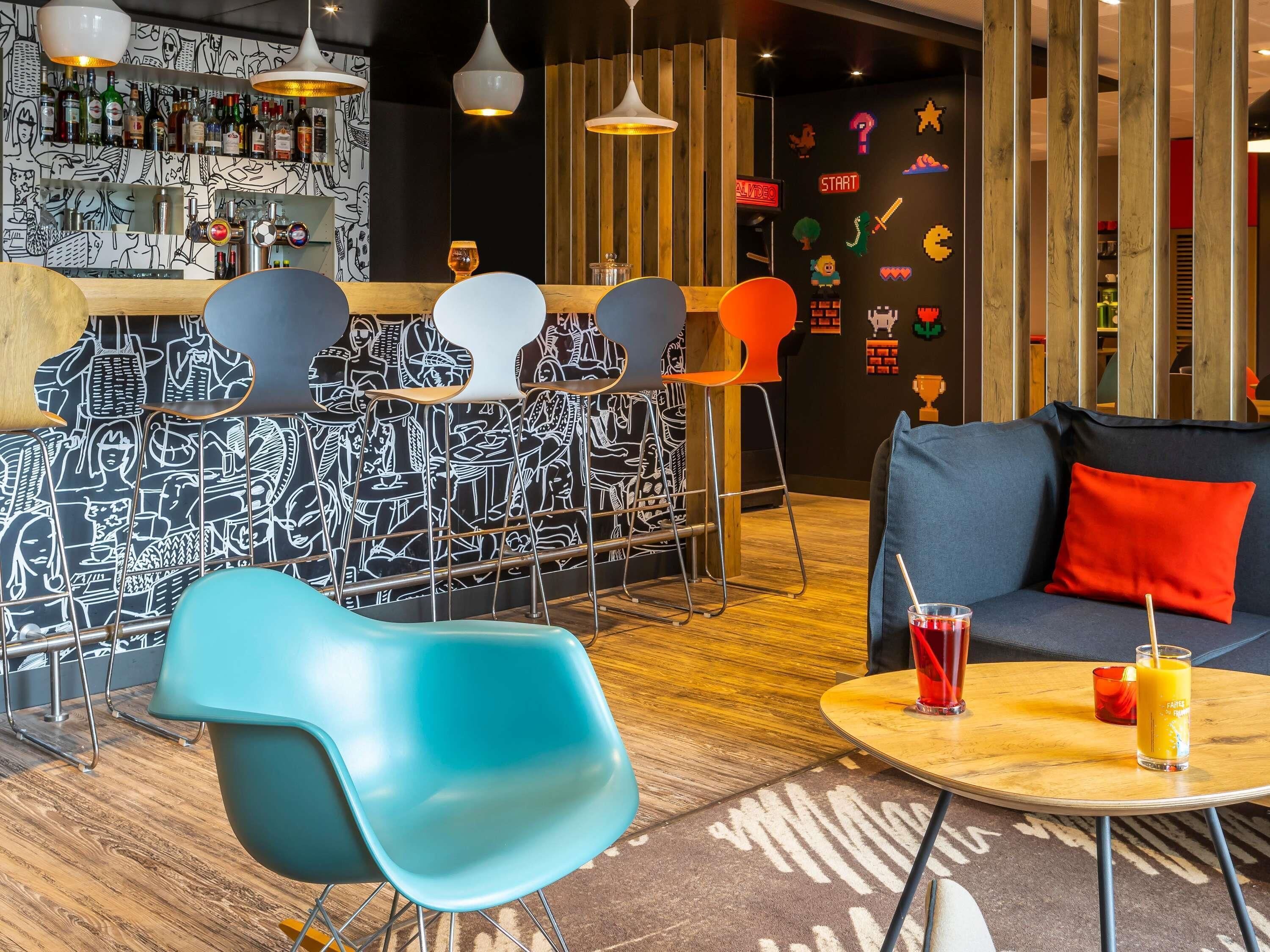 Uma área de bar com balcão, banquetes e um sofá com almofada vermelha.