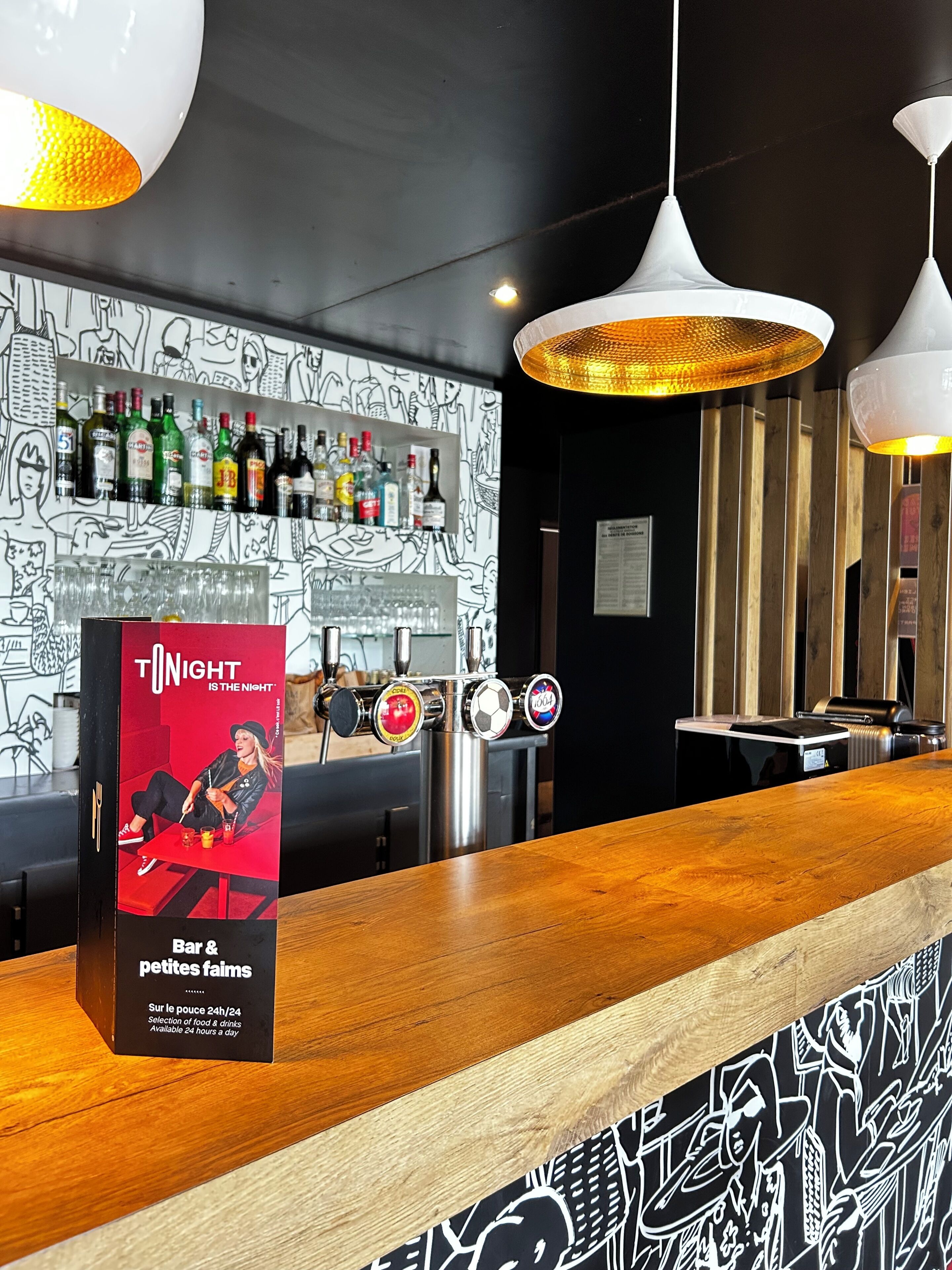 A bar area with a sign for 'Bar & petites faims' and a selection of drinks available 24 hours.