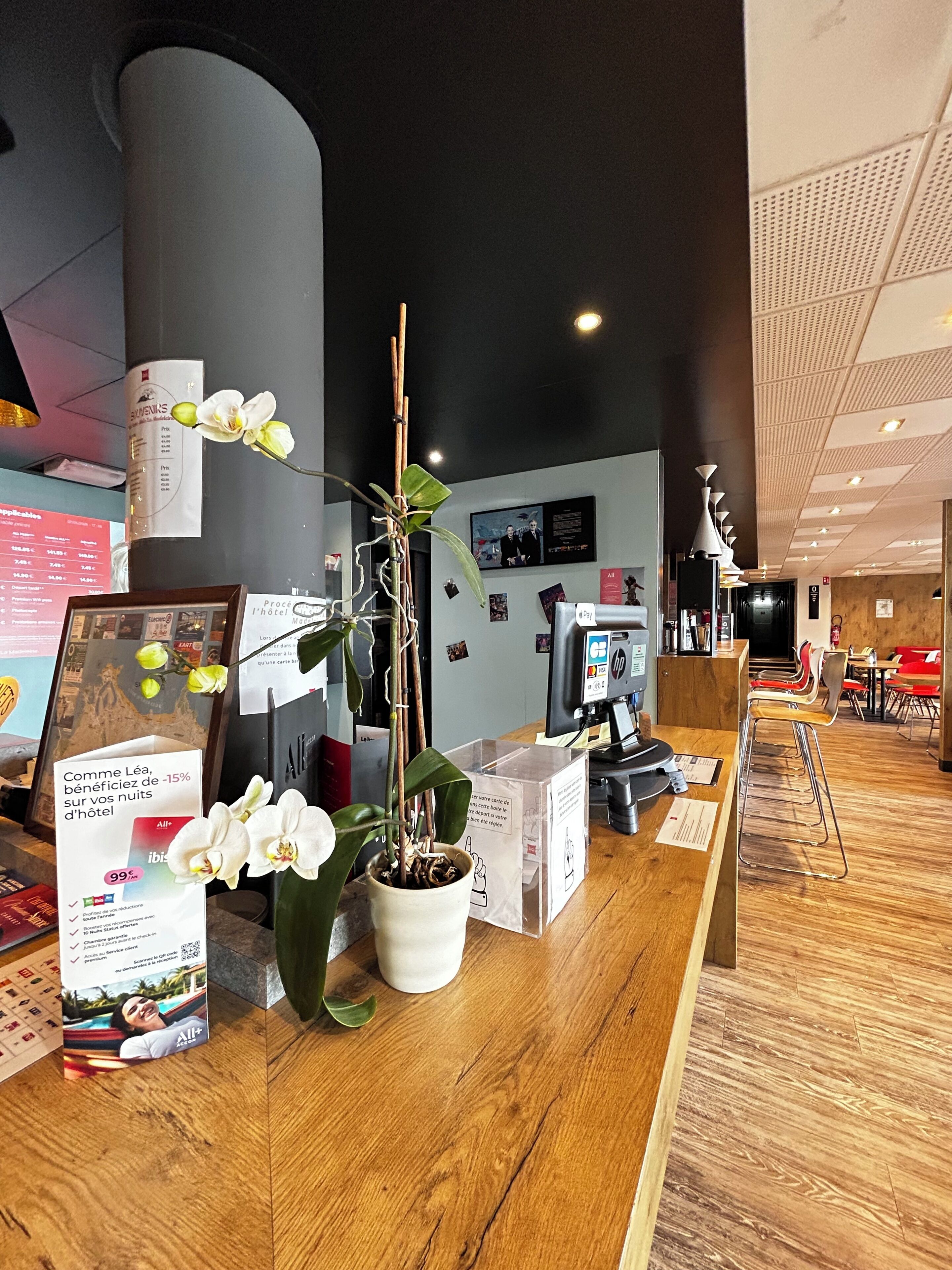 Un comptoir d’accueil agrémenté d’une plante en pot, d’un tableau encadré et de brochures d’information.