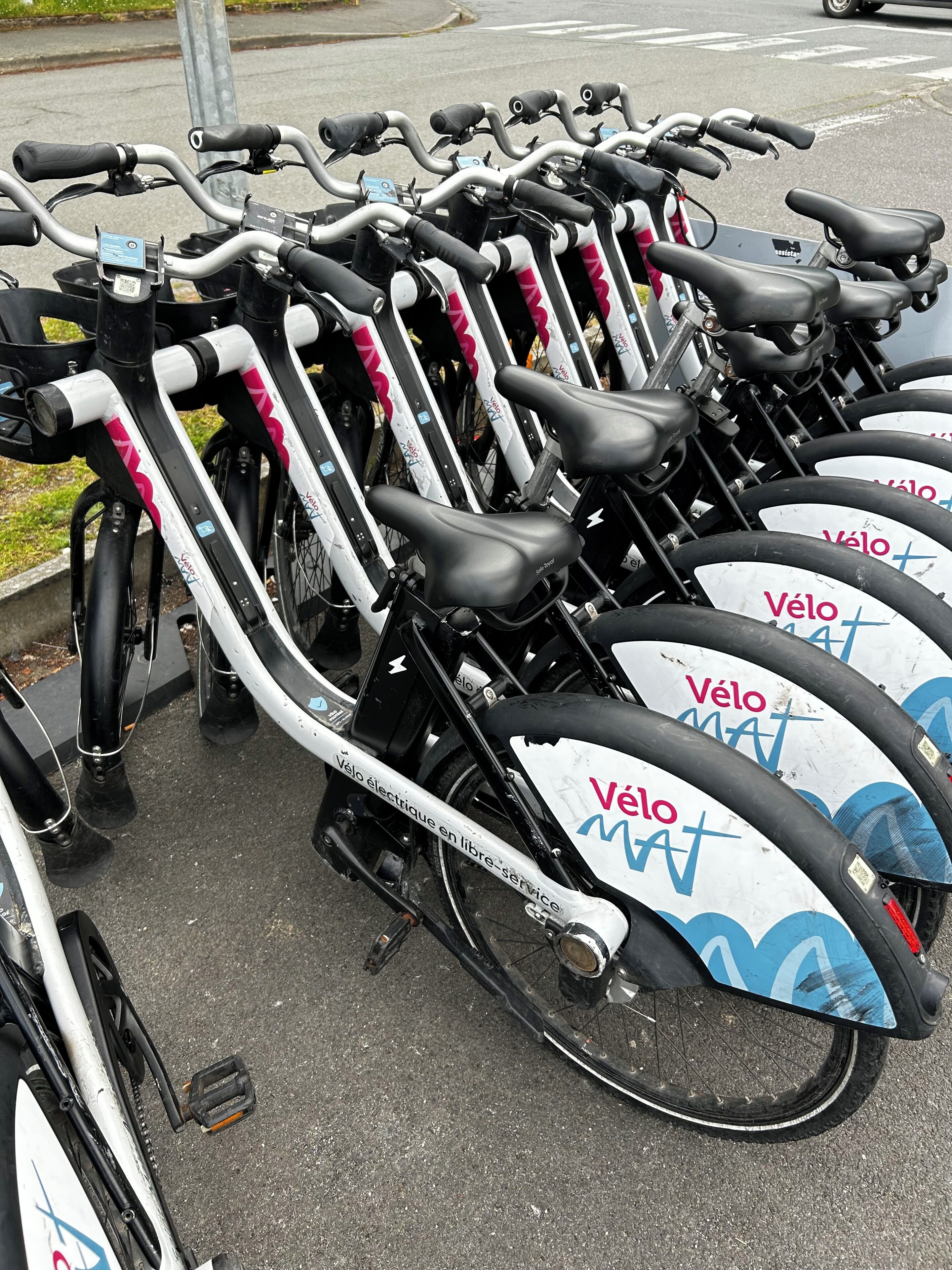 Une rangée de vélos électriques Vélo Mat est stationnée dans un espace prévu à cet effet.
