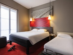 Ein Hotelzimmer mit zwei Betten, einem roten Teppich und einem großen Fenster.