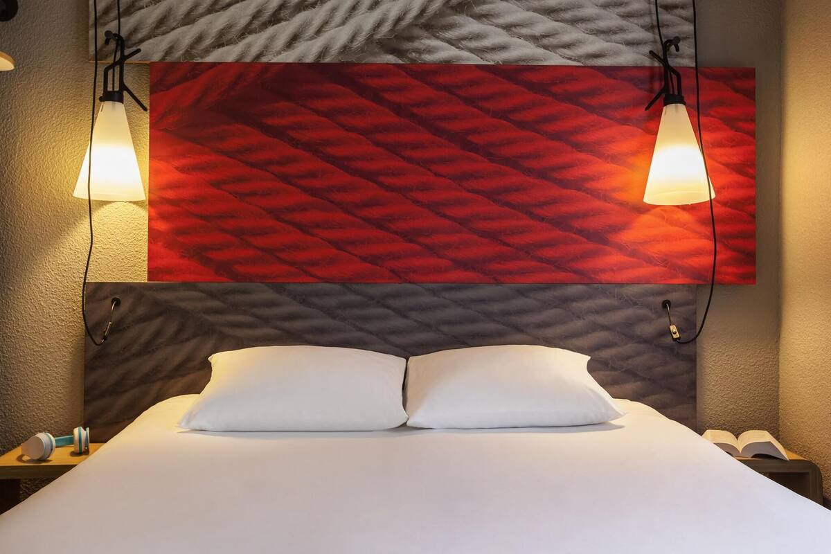 Une chambre d’hôtel avec un lit, deux lampes de chevet et un mur à motifs au-dessus du lit.