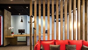 Un espace de bureau moderne avec un canapé rouge, des lambris en bois, un bureau avec un ordinateur et une plante.