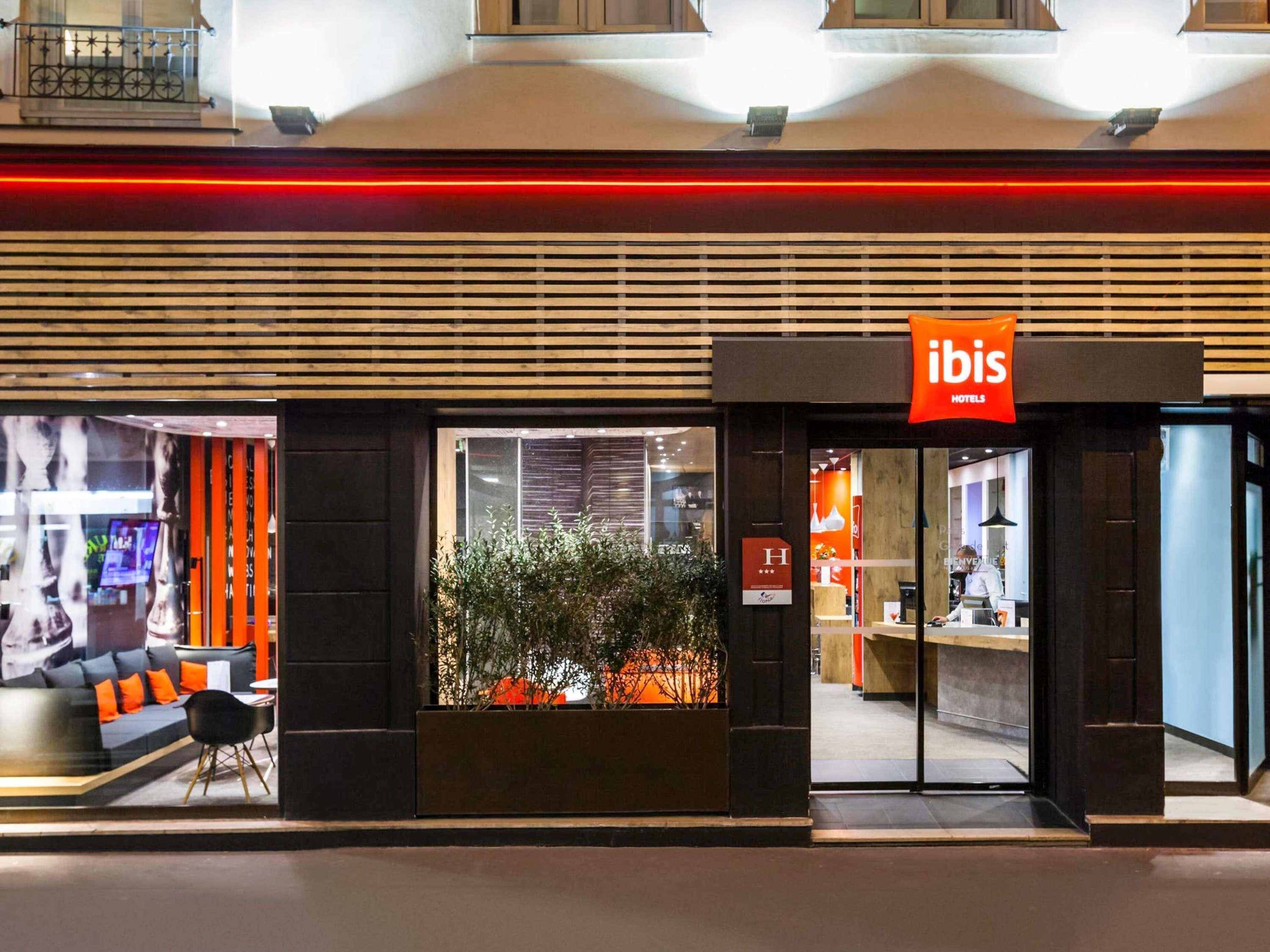L’entrée d’un hôtel présente un design moderne, avec un comptoir d’accueil et un espace de détente intérieur bien visible.