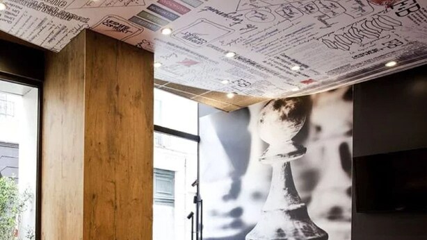 Un espace de détente moderne agrémenté d’une grande fresque représentant un échiquier, de meubles en bois et d’un aménagement confortable.