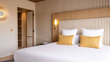 Una habitación de hotel con una cama grande, un cabecero de madera, una mesita de noche, una lámpara y un armario.