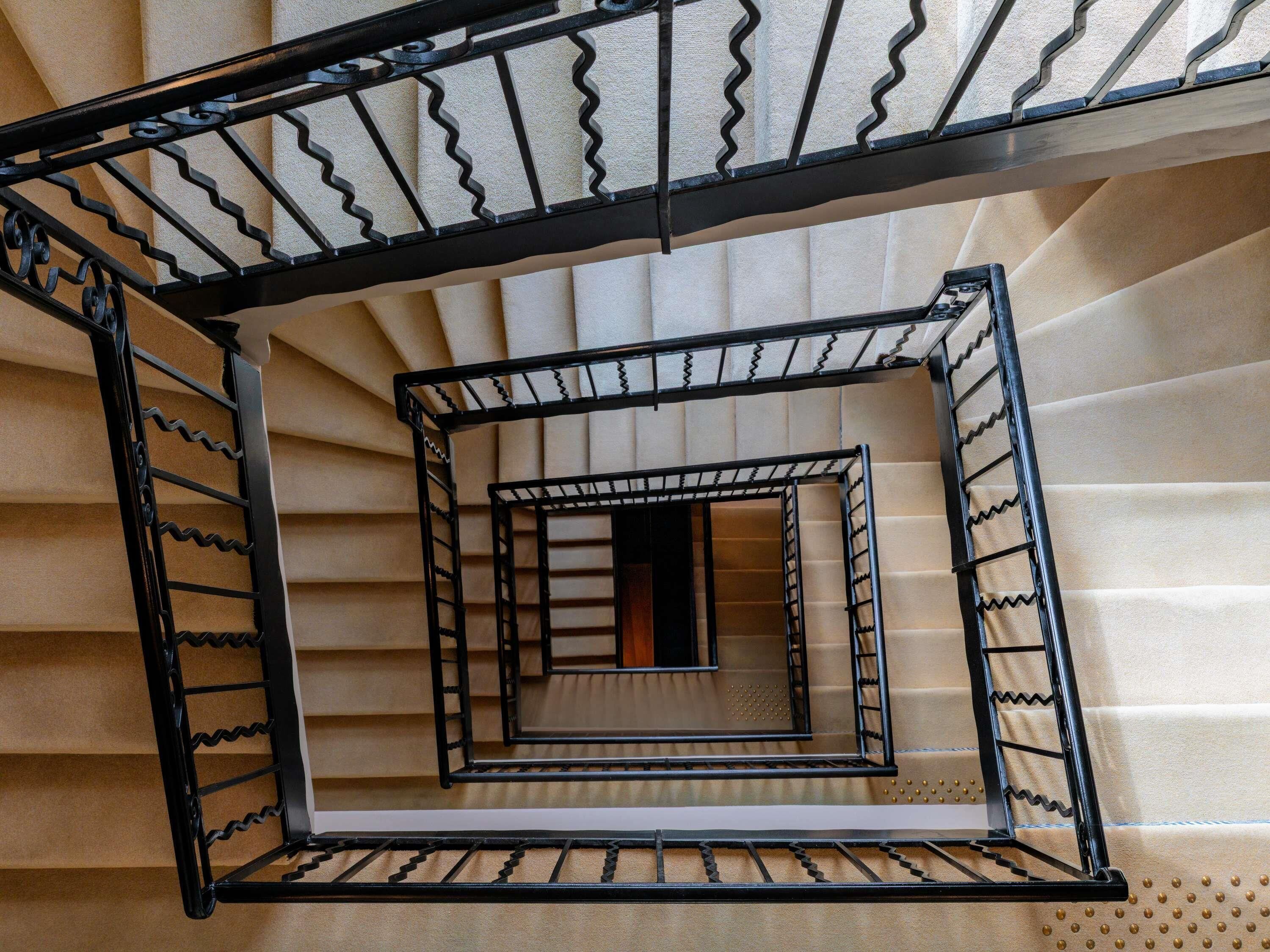 A spiral staircase with a metal railing, leading to an upper floor.