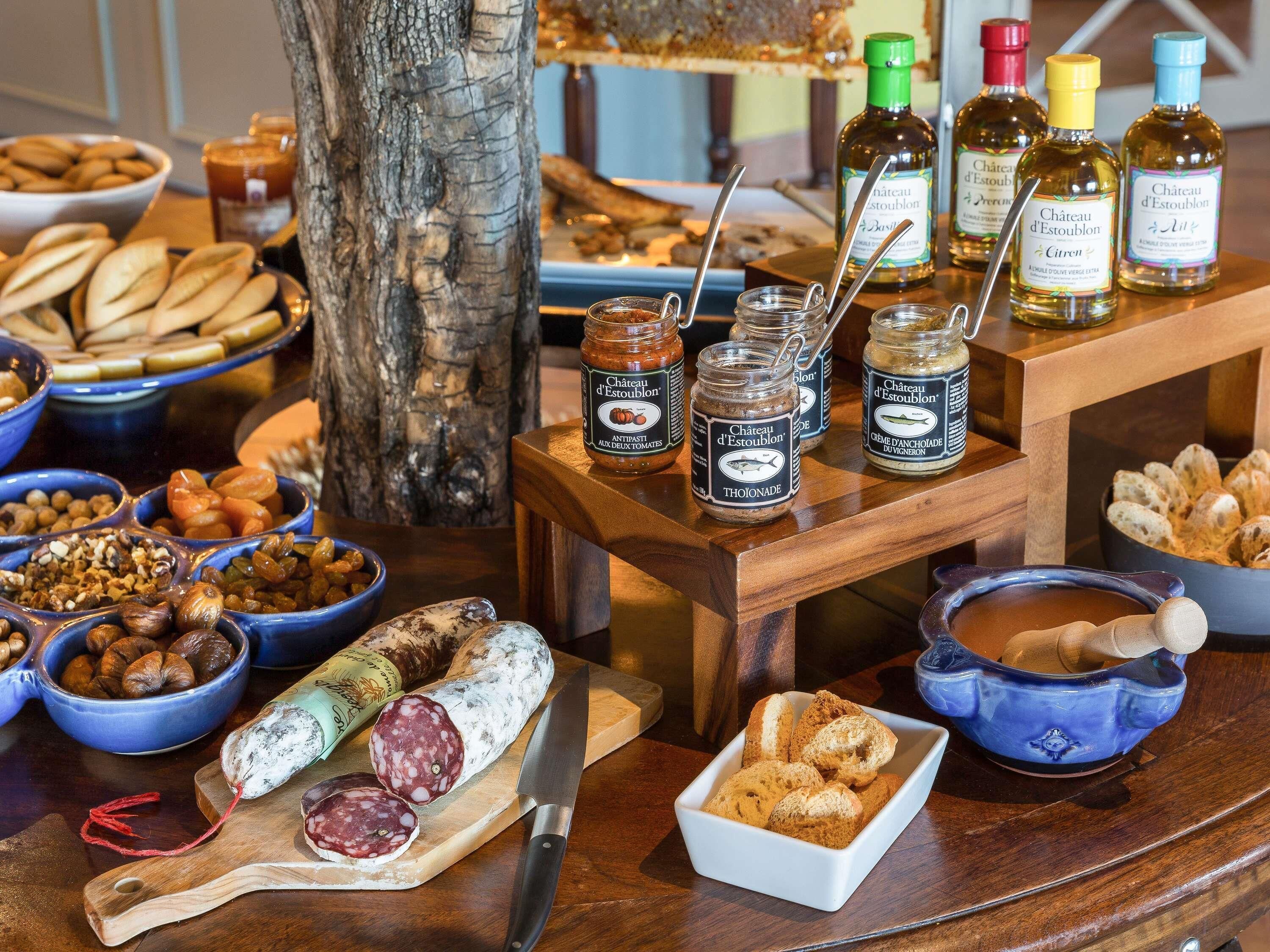 Una mesa de buffet con diferentes alimentos, como pan, frutos secos y frascos de conservas.