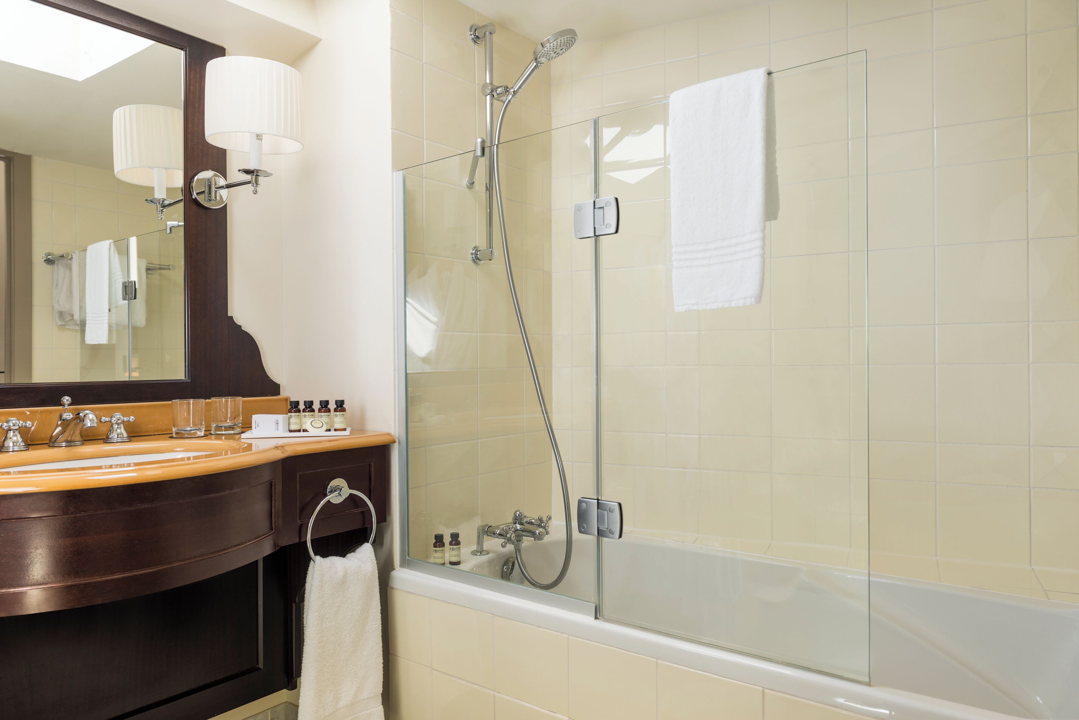 Une salle de bain avec une douche à parois de verre, un meuble-lavabo en bois avec un miroir et une baignoire.