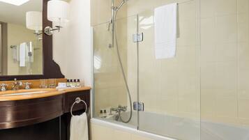 Een badkamer met een douche met glazen wand, een houten wastafelmeubel met spiegel en een bad.