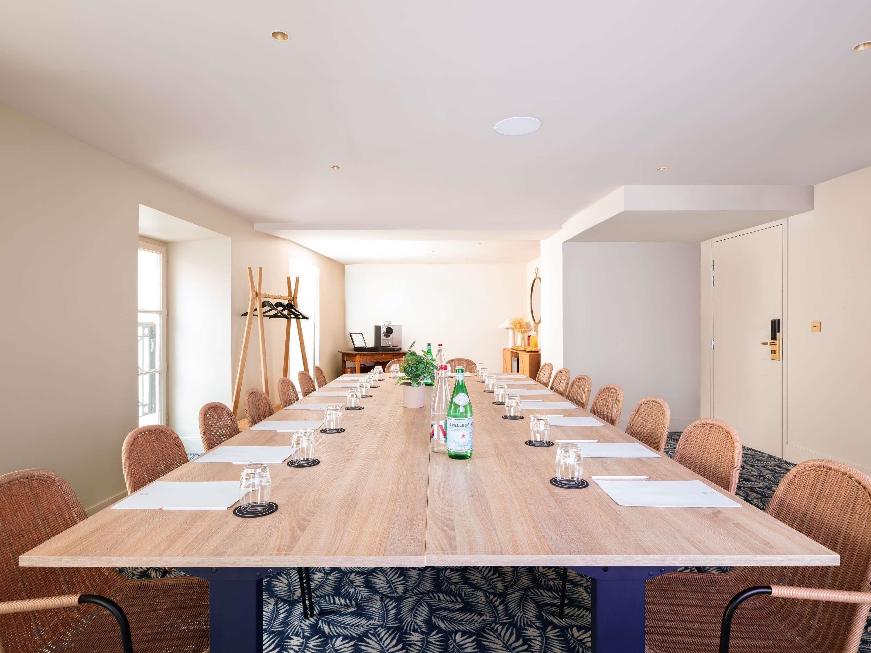 Ett konferensrum med ett långt bord, stolar och en växt som står som mittpunkt.