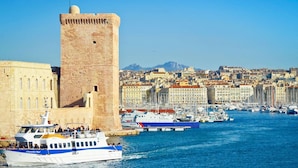 A historic tower and a waterfront cityscape with a boat docked in the foreground. - Grand Hotel Beauvau Marseille Vieux-Port - MGallery Collection (Marseille)