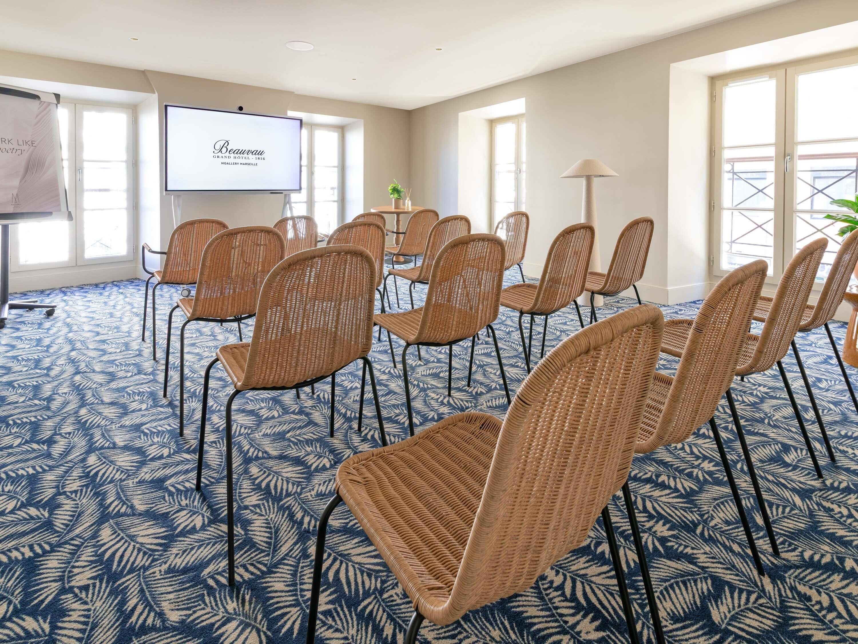 A conference room with wicker chairs, a projector screen, and a patterned carpet.