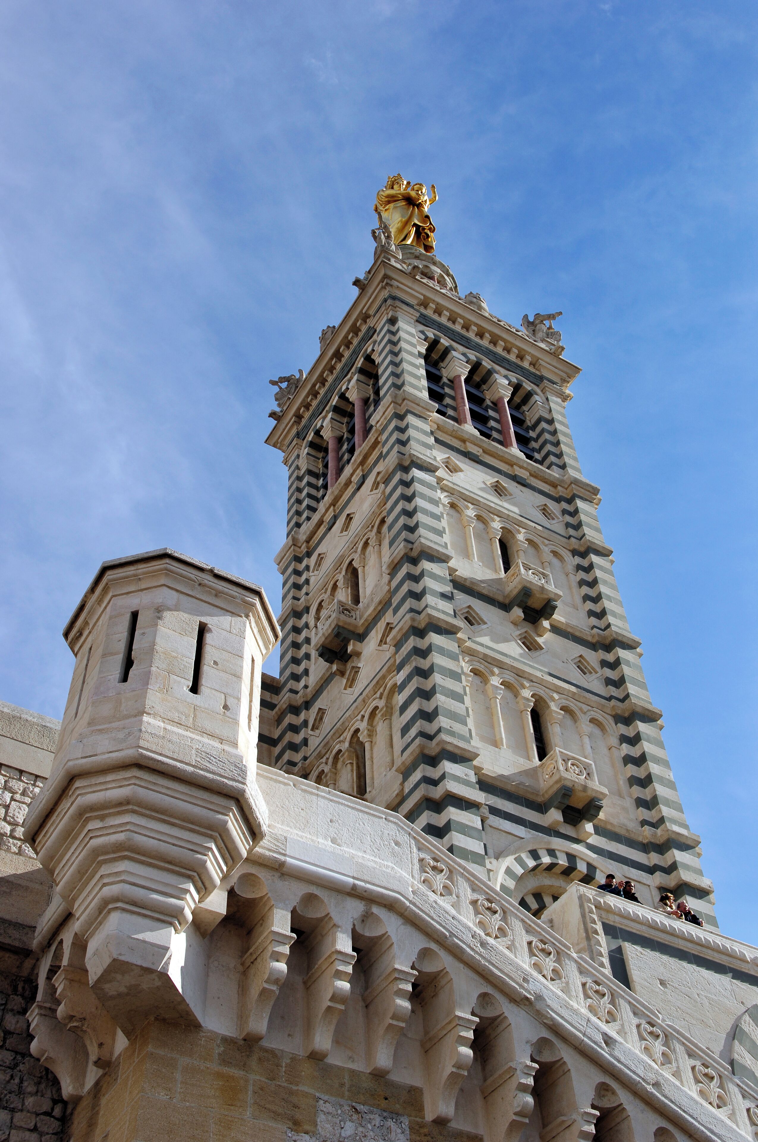 A historic tower with intricate stone carvings and a golden statue on top.