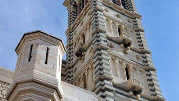 A historic tower with intricate stone carvings and a golden statue on top.