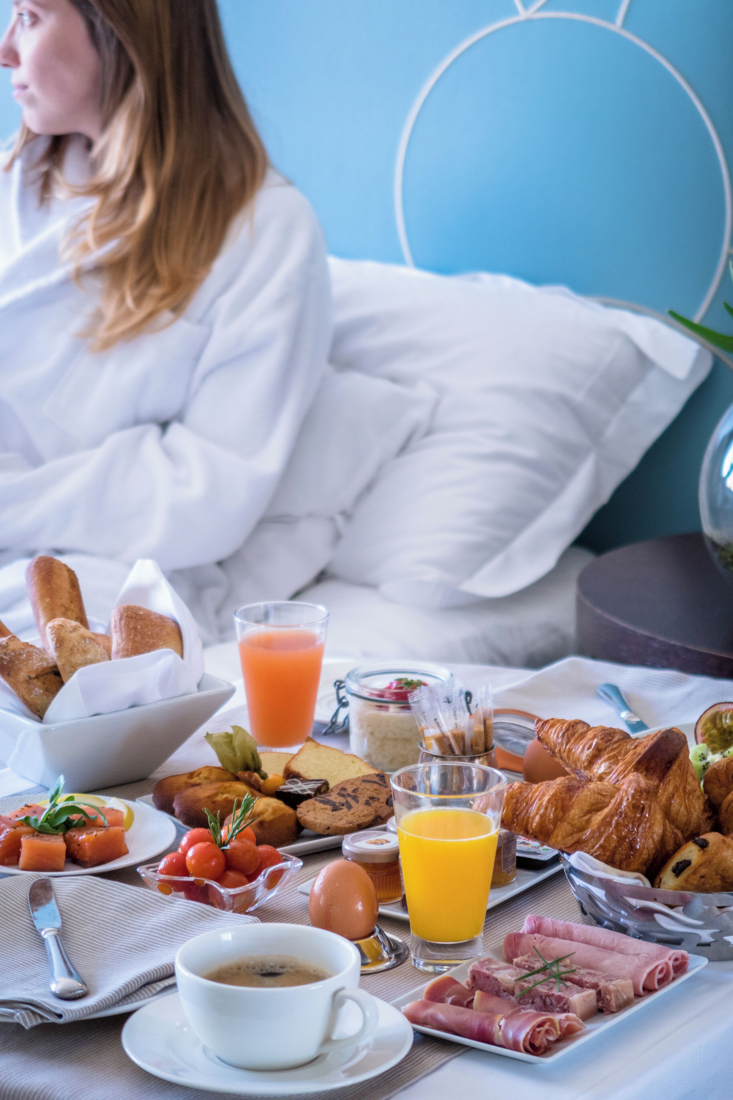 Une table de petit-déjeuner avec des croissants, des œufs, des tomates et du jus de fruits.