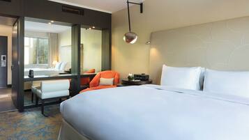 A hotel room with a large bed, a desk, a chair, and a bathroom visible through an open door.