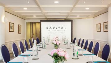 A conference room with a long table, chairs, and a screen displaying the Sofitel Hotels & Resorts logo.
