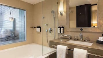 A modern bathroom with a glass-enclosed shower, a large mirror, and a bathtub.