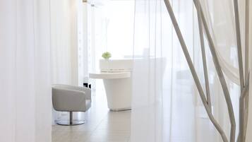 Un baño moderno con un lavamanos blanco, un espejo y una silla.