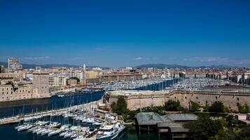 A marina with numerous boats docked, surrounded by historic buildings and a clear blue sky.