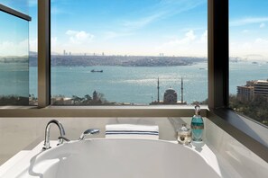 A bathroom with a large window offering a view of a city skyline and a body of water.