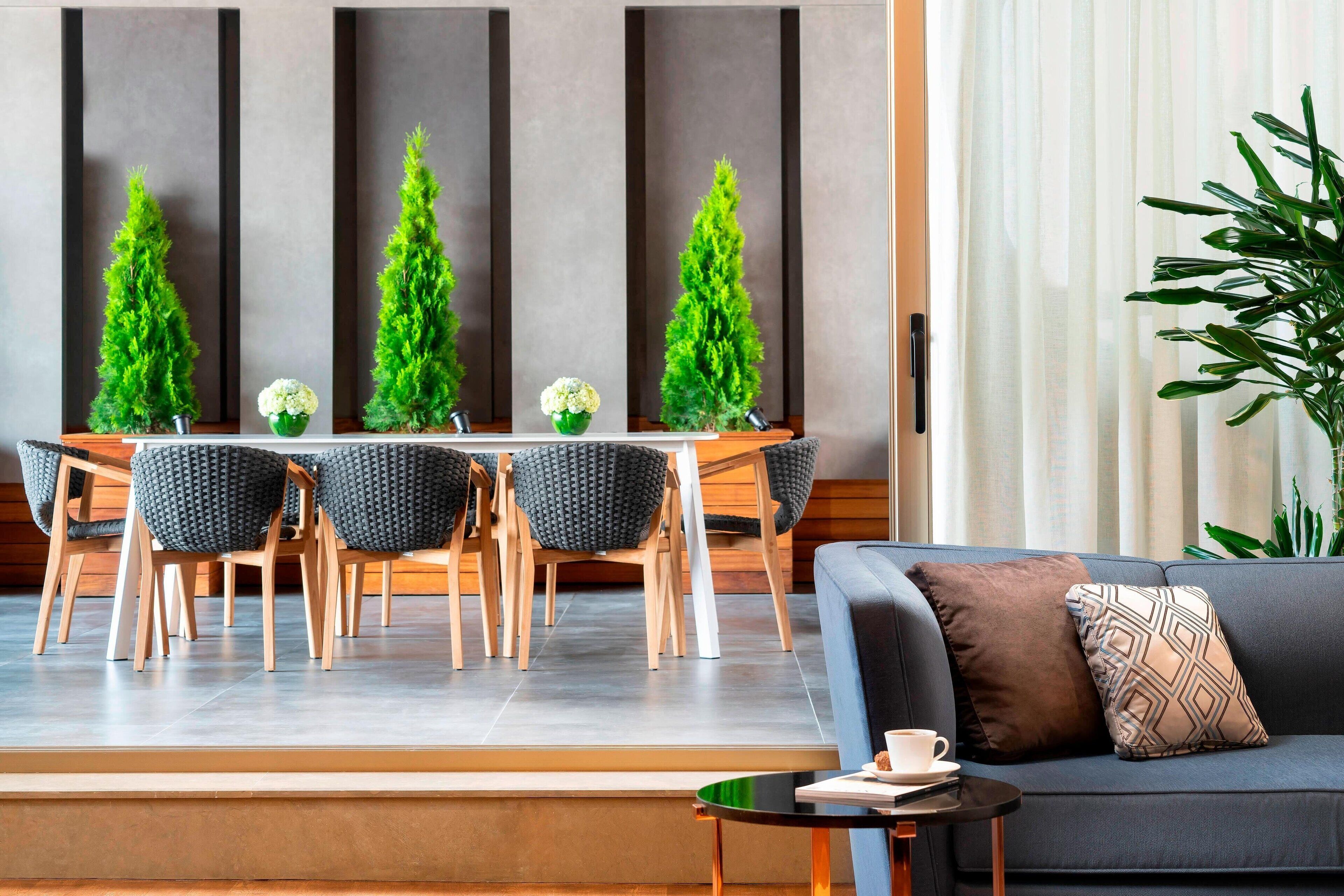 A modern living room with a sofa, a coffee table, and a dining area with a table and chairs.