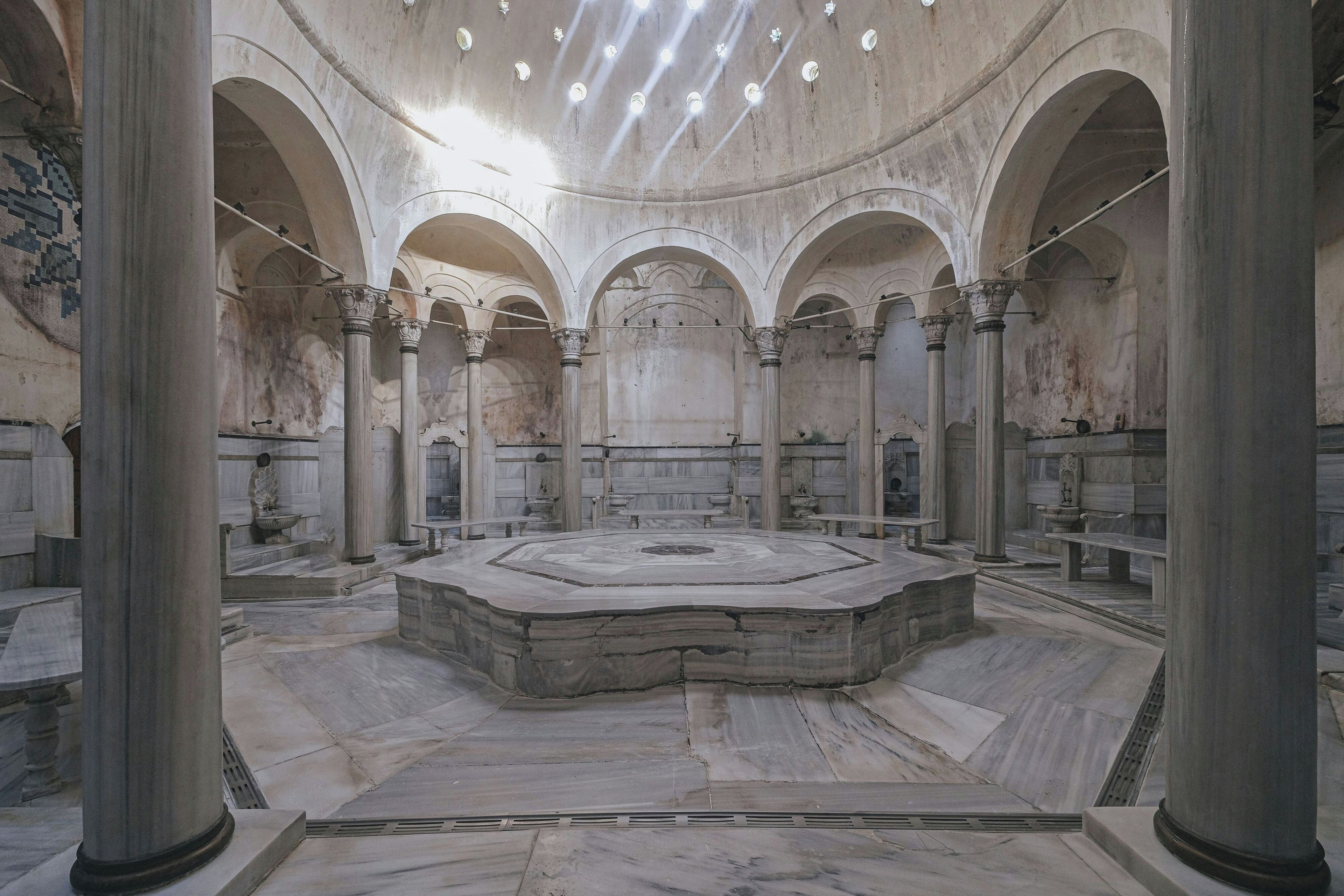Un vaste hall doté d’une plateforme circulaire centrale, entourée d’arcades et de colonnes.