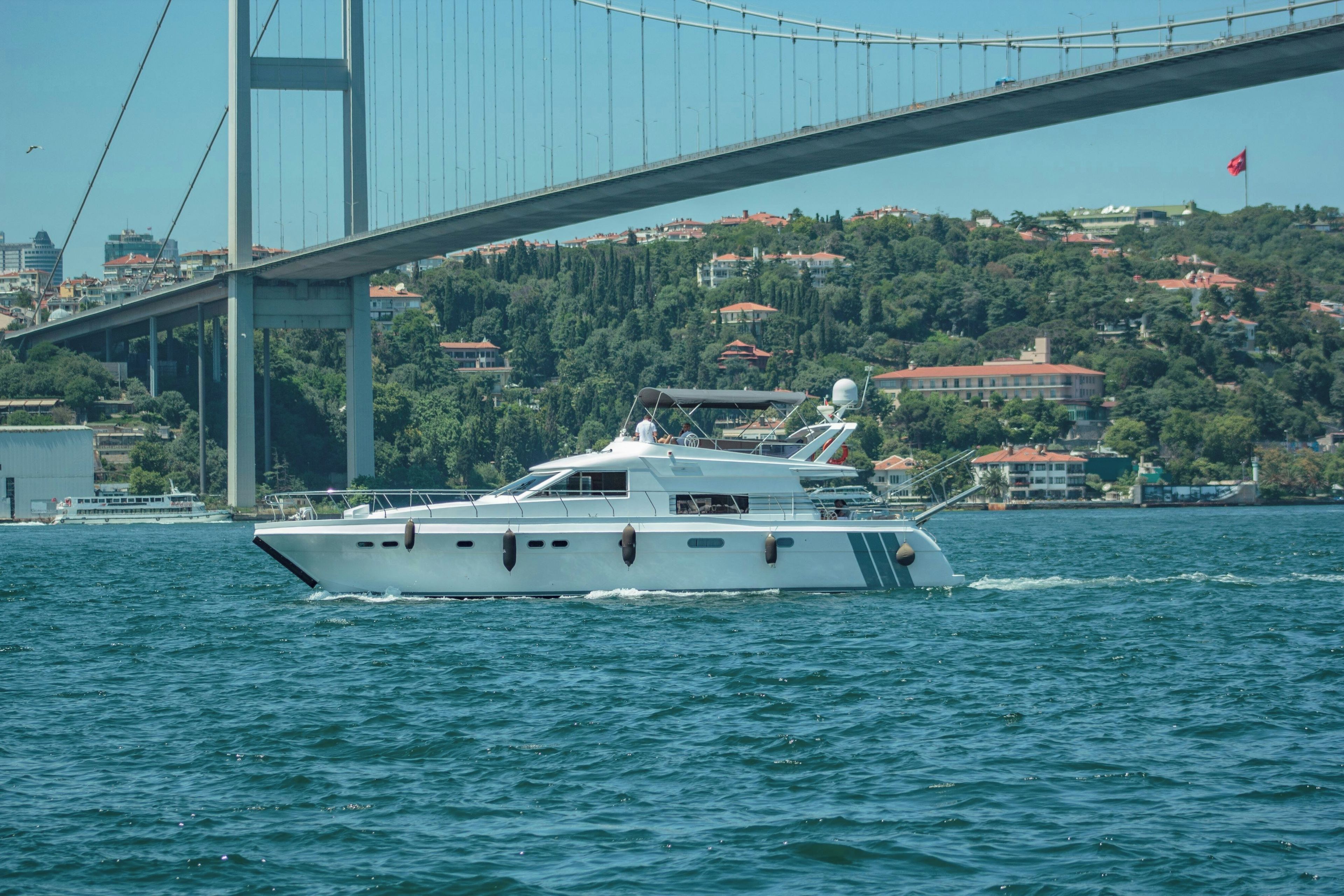 Eine Yacht auf dem Wasser, im Hintergrund eine Brücke.