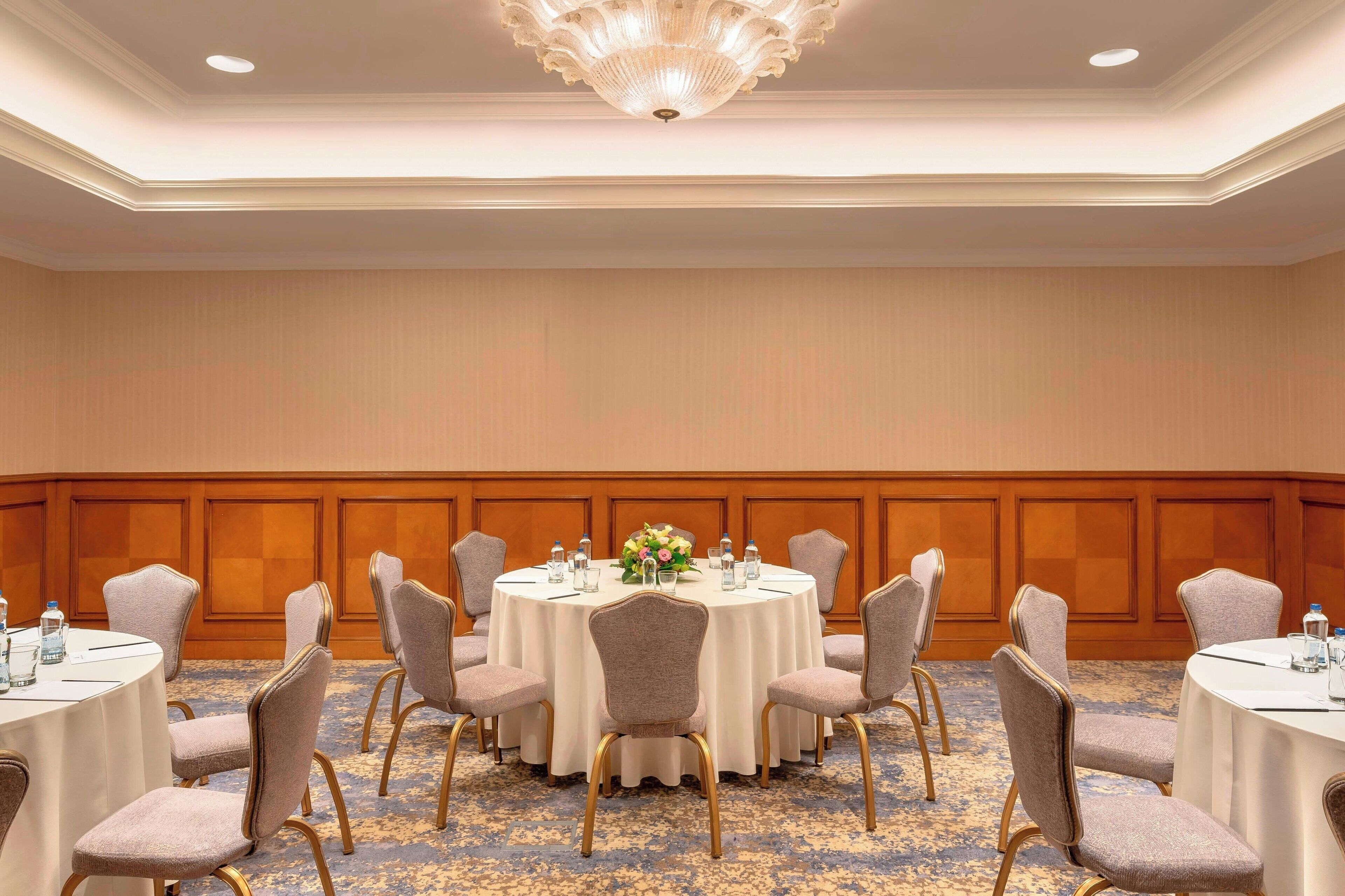 Una sala de conferències amb taules rodones, cadires i un candelabrum.