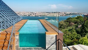 A rooftop infinity pool with a clear view of the city skyline and the sea.