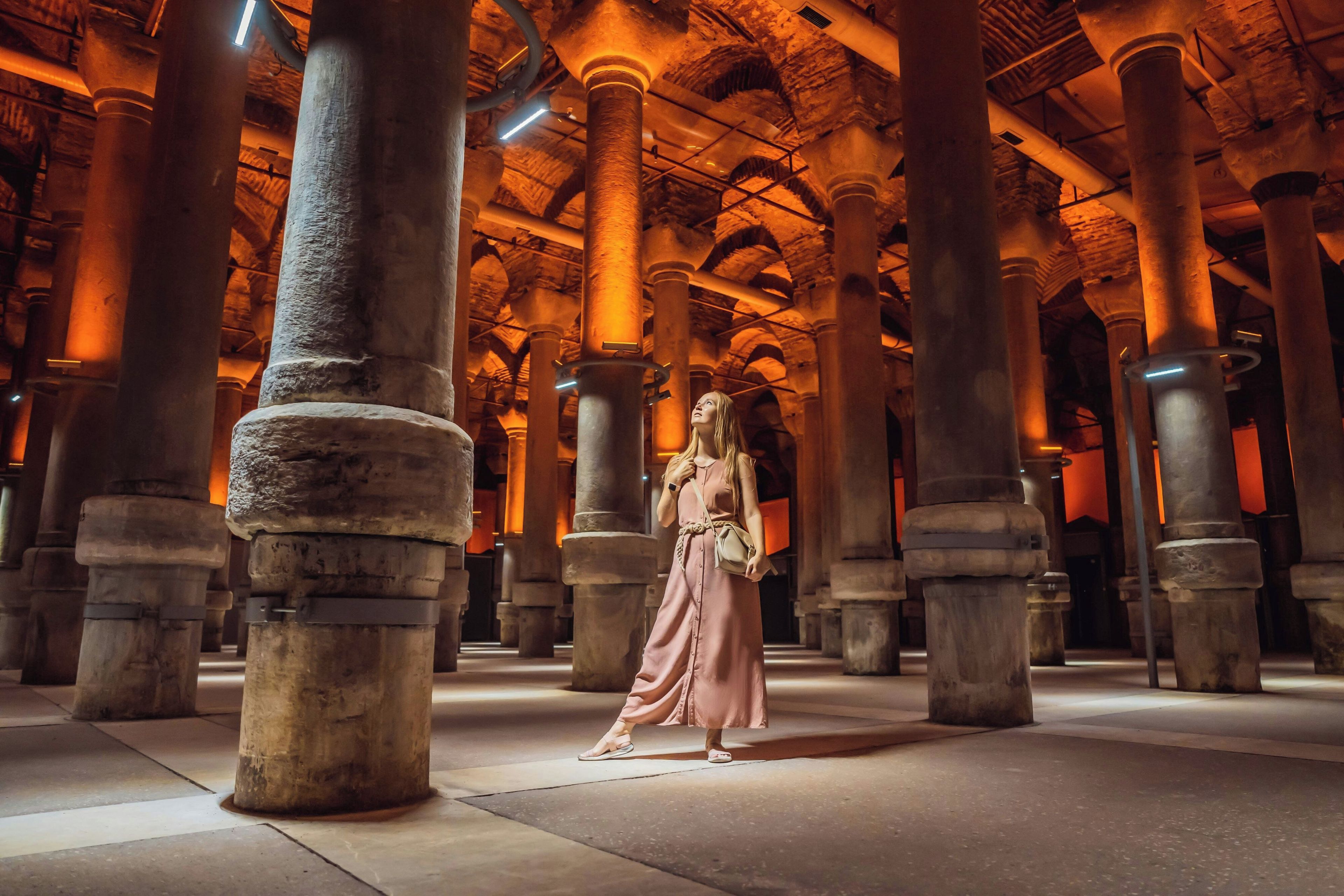 A spacious interior with high stone columns and a person standing in the center.