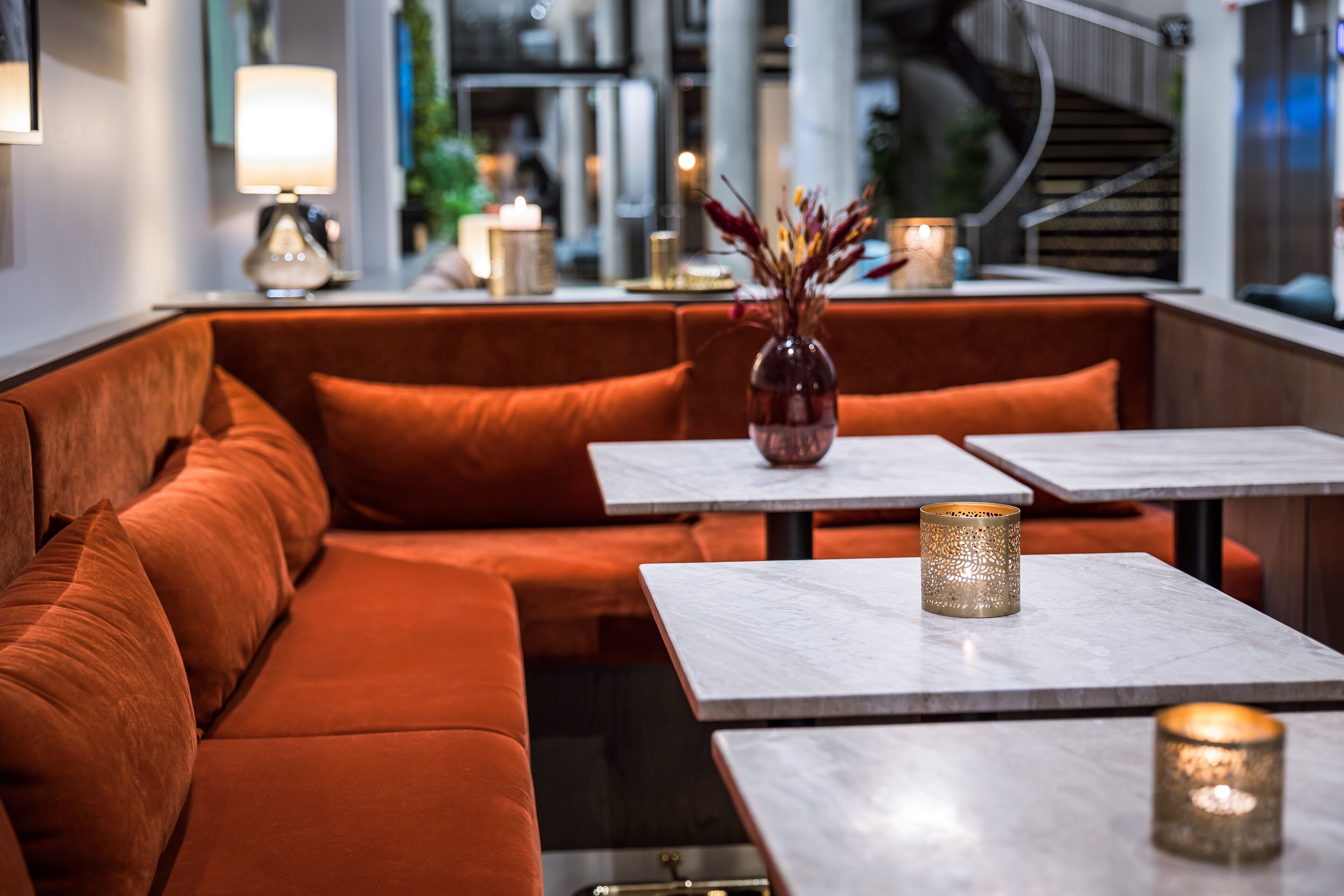 A modern interior with a sofa and tables, a vase with dried flowers, and candles on the tables.