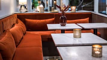 A modern interior with a sofa and tables, a vase with dried flowers, and candles on the tables.