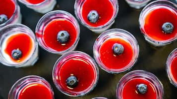 Multiple glasses of a red beverage with blueberries.