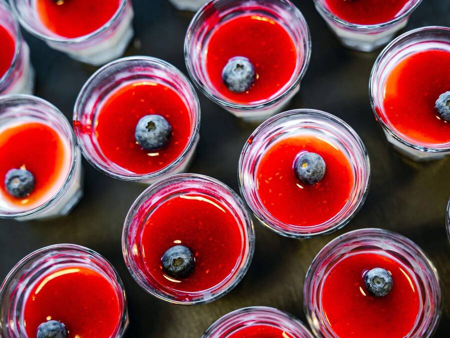 Multiple glasses of a red beverage with blueberries.