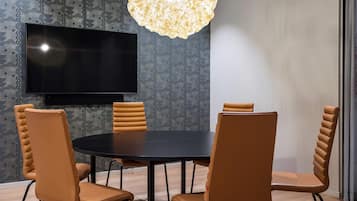 A conference room with a round table, four chairs, a flat-screen TV, and a patterned wallpaper.