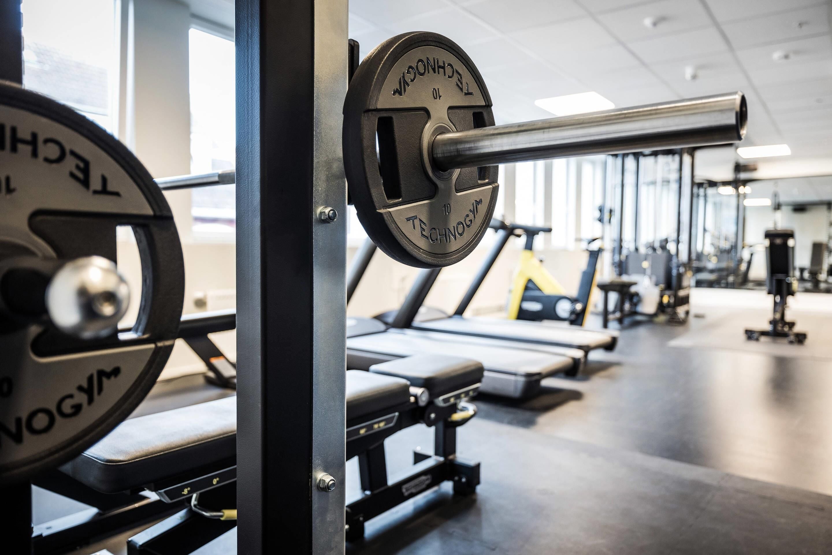 Un gimnasio con equipos de levantamiento de pesas y cintas de correr.