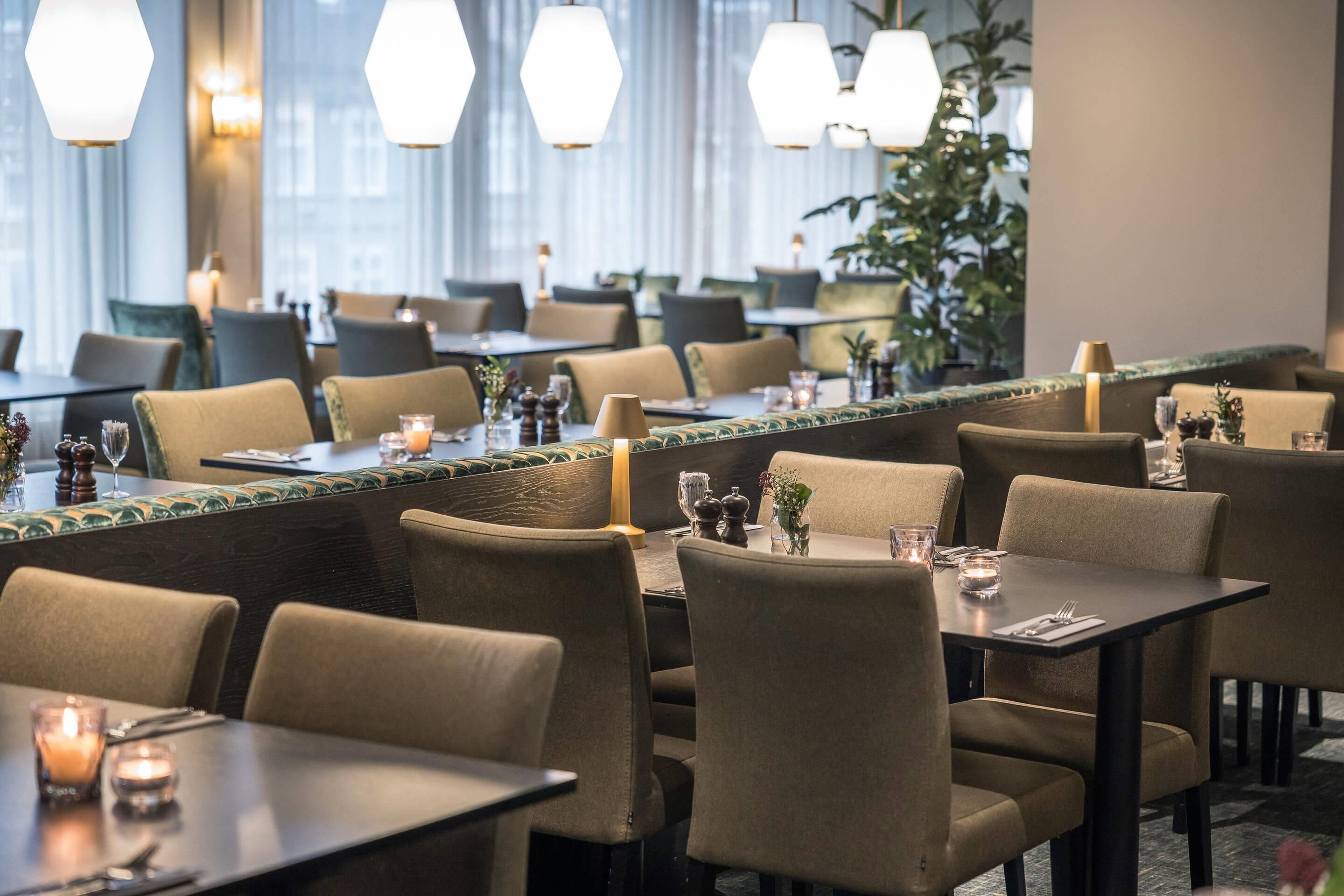 Un restaurant doté de nombreuses tables et chaises, chacune agrémentée de bougies et de petits vases.
