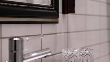 A bathroom with a black sink, a mirror, and a hand soap dispenser on the wall.