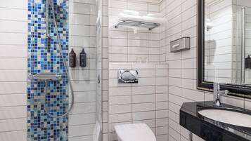 A bathroom with a shower, toilet, sink, and mirror.