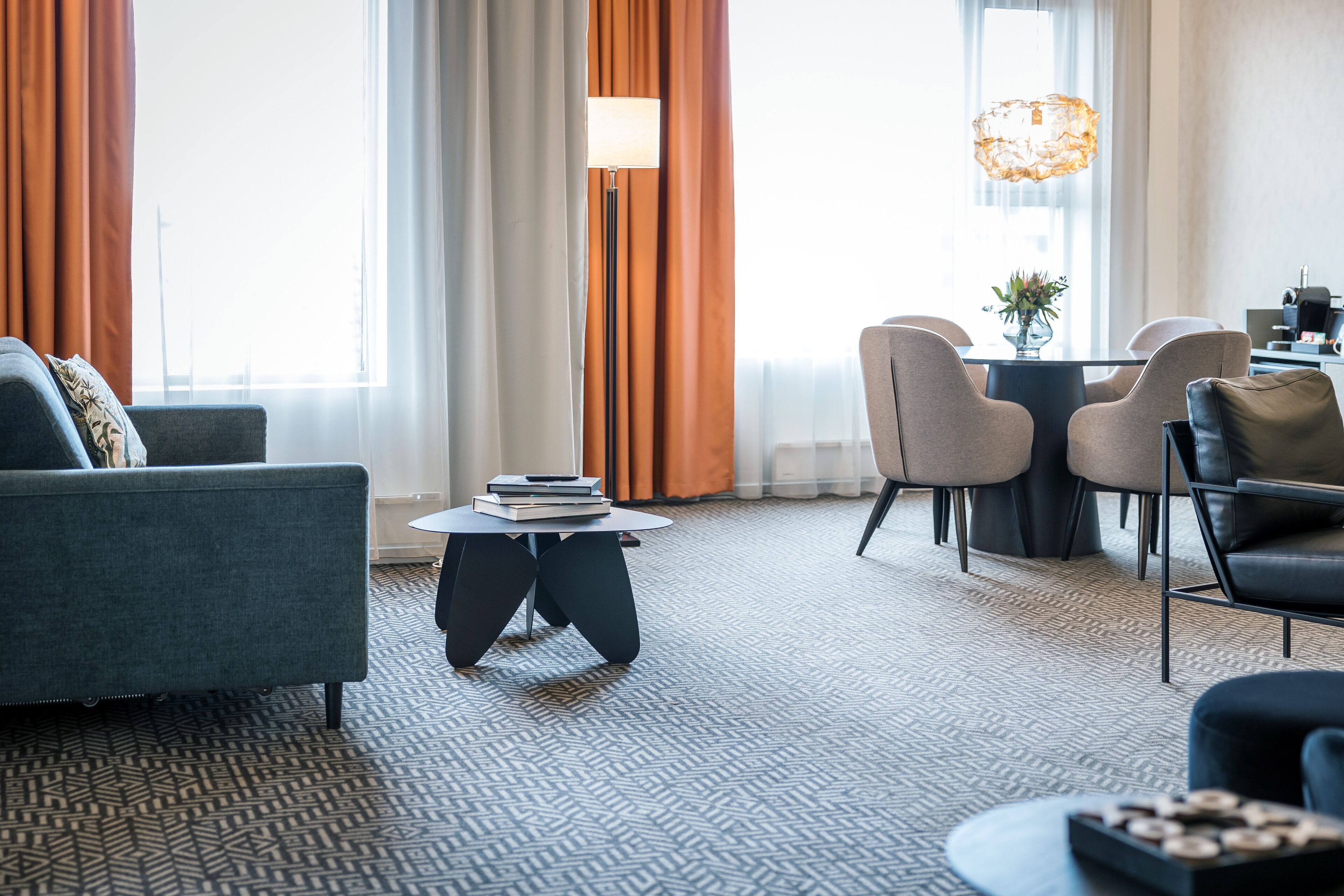 Une chambre d’hôtel moderne avec un canapé, une table basse ronde et un coin repas comprenant des chaises et une table.