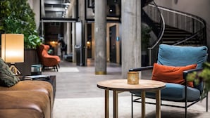 A modern lobby with a curved staircase, leather seating, and a coffee table. - Quality Hotel Prinsen (Trondheim)