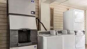 Un área de lavandería con lavadora y secadora industriales, un calentador de agua y un sistema de ventilación.